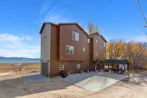Rear view of house with faux log siding, a water view, and a patio