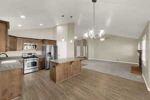 Kitchen featuring stainless steel appliances, a fireplace, a kitchen island, pendant lighting, and open floor plan