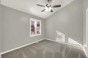 Unfurnished room featuring lofted ceiling, carpet flooring, and a ceiling fan