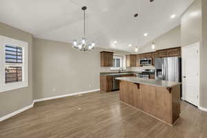 Kitchen with appliances with stainless steel finishes, hanging light fixtures, a kitchen breakfast bar, a chandelier, and recessed lighting