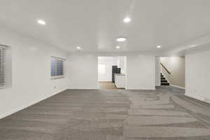 Below grade area with recessed lighting, light colored carpet, and stairs