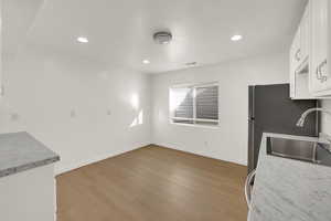 Kitchen featuring white cabinets, light countertops, light wood-type flooring, recessed lighting, and freestanding refrigerator