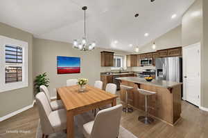 Dining room with light wood finished floors, a chandelier, recessed lighting, and high vaulted ceiling