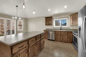 Kitchen with appliances with stainless steel finishes, a center island, hanging light fixtures, recessed lighting, and light wood finished floors