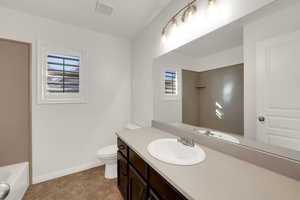Bathroom featuring healthy amount of natural light, a bath, vanity, and light tile patterned floors
