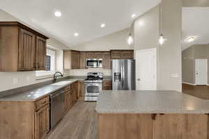 Kitchen with light wood finished floors, stainless steel appliances, decorative light fixtures, a kitchen bar, and a center island