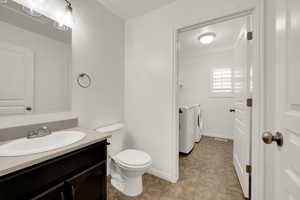 Half bath featuring washer and dryer, vanity, and light tile patterned floors