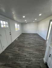 Foyer entrance featuring a textured ceiling, dark wood-style flooring, and recessed lighting