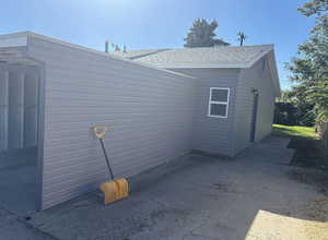 View of side of home with a shingled roof