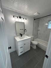 Full bath with vanity, a textured ceiling, dark tile patterned flooring, and shower / bathtub combination