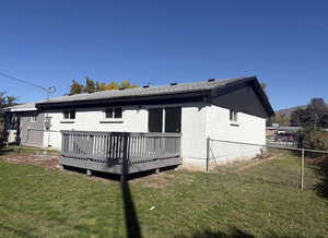 Rear view of house with a wooden deck, brick siding, and roof with shingles