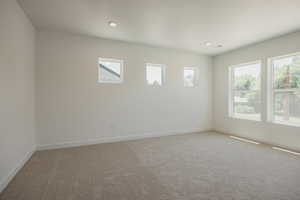 Empty room with light colored carpet and recessed lighting