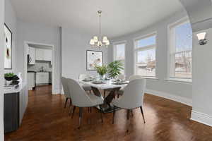 Dining room with dark wood-style flooring and suspended lighting