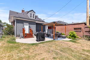 Rear view of property featuring a patio, a chimney, a shingled roof, and an outdoor living space