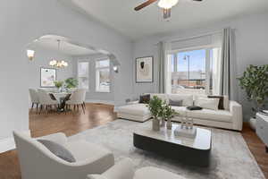 Living area featuring suspended lighting, wood finished floors, arched walkways, and a ceiling fan
