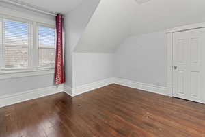 Bonus room with dark wood finished floors and lofted ceiling