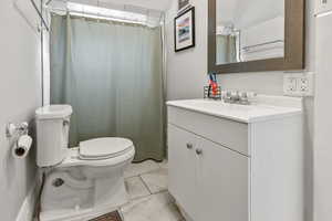 Full bathroom with curtained shower, vanity, and light tile patterned floors