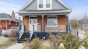 View of front facade featuring covered porch and brick siding