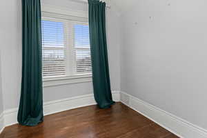 Spare room featuring dark wood finished floors and lofted ceiling