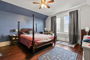 Bedroom featuring lofted ceiling, dark wood-style floors, and a ceiling fan