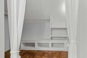 Walk in closet with parquet flooring