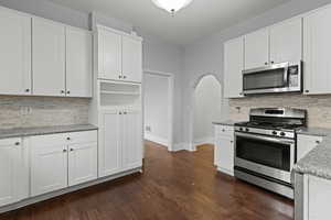 Kitchen featuring decorative backsplash, stainless steel appliances, and white cabinetry