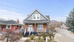 View of front of home with a porch, roof with shingles, and brick siding