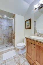 Full bathroom featuring vanity, a shower stall, light tile patterned flooring, and vaulted ceiling