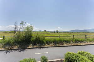 View of asphalt street with a view of rural / pastoral area and a mountain view