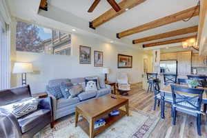 Living room with beamed ceiling, light wood-style floors, and recessed lighting