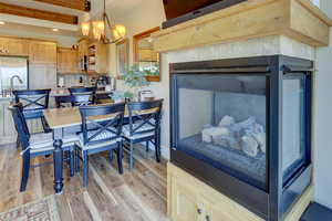 Dining room featuring light wood-style floors, beam ceiling, a chandelier, and recessed lighting