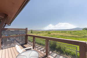 Wooden terrace with outdoor dining area and a view of rural / pastoral area