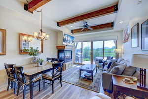 Living area with beamed ceiling, a multi sided fireplace, wood finished floors, ceiling fan, and recessed lighting