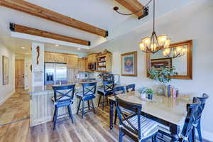 Dining room with beam ceiling, recessed lighting, light wood-type flooring, and a chandelier