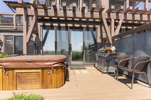 Wooden terrace featuring a hot tub and a pergola