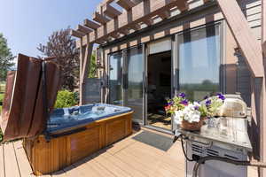 Wooden deck featuring a hot tub and a pergola