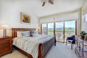 Bedroom with lofted ceiling, light colored carpet, a ceiling fan, and access to exterior