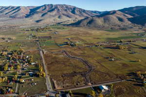 Expansive land parcel featuring partial road infrastructure, surrounded by open fields and distant mountains