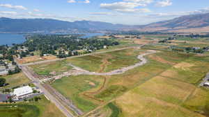 Expansive land parcel featuring open fields, partially developed roadways, and a winding natural waterway