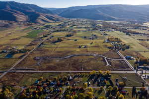 Expansive valley landscape showcasing a mix of open fields, wooded areas, and scattered residential properties