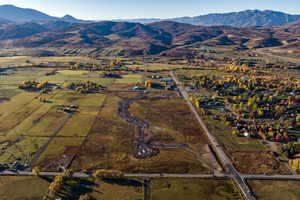 Expansive land parcel featuring cleared areas for development, an established roadway, and surrounding agricultural fields