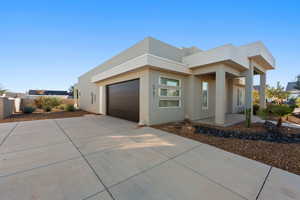 Contemporary house featuring driveway, stucco siding, and a garage