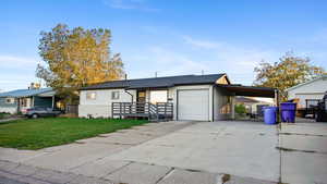 View of front of property featuring a front yard, concrete driveway, and a carport