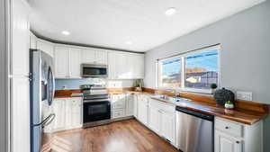 Kitchen, appliances with stainless steel finishes, white cabinetry, recessed lighting, and dark wood-style floors