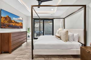 Bedroom featuring a ceiling fan, wood finished floors, a tray ceiling, and recessed lighting