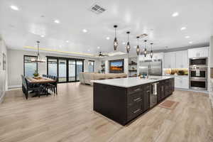 Kitchen with ceiling fan, white cabinetry, pendant lighting, a raised ceiling, and backsplash