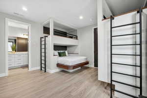 Bedroom featuring light wood finished floors, recessed lighting, and connected bathroom
