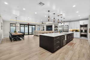 Kitchen featuring a ceiling fan, white cabinetry, hanging light fixtures, a tray ceiling, and decorative backsplash