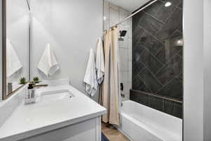 Full bath featuring shower / bathtub combination with curtain, vanity, and light wood-style flooring