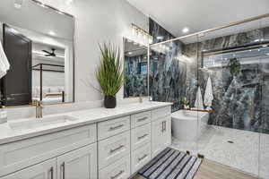 Full bathroom with double vanity, a marble finish shower, a freestanding tub, ceiling fan, and recessed lighting